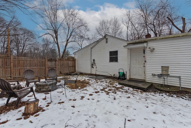 snow covered back of property with a fire pit