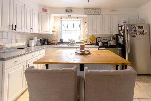 kitchen featuring white cabinets, sink, stainless steel fridge, and decorative backsplash