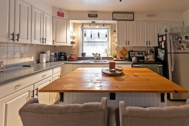 kitchen featuring sink, backsplash, white cabinets, and stainless steel refrigerator