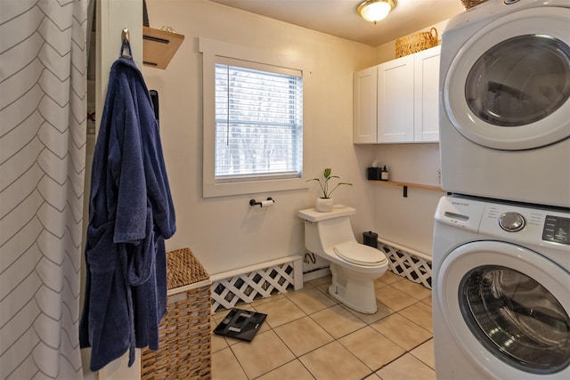 laundry area featuring stacked washing maching and dryer, a baseboard heating unit, and light tile patterned flooring