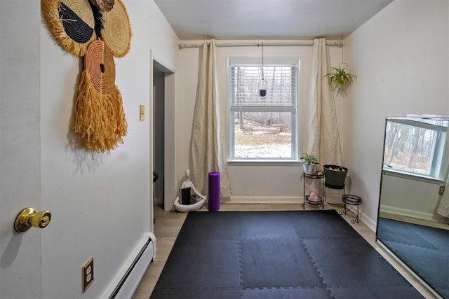 workout room with light wood-type flooring and baseboard heating