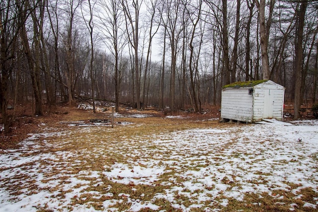 yard layered in snow featuring a shed