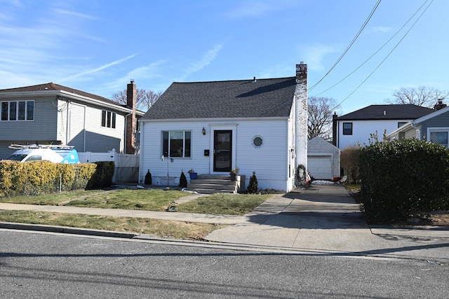 view of front facade featuring an outbuilding, a garage, and a front lawn