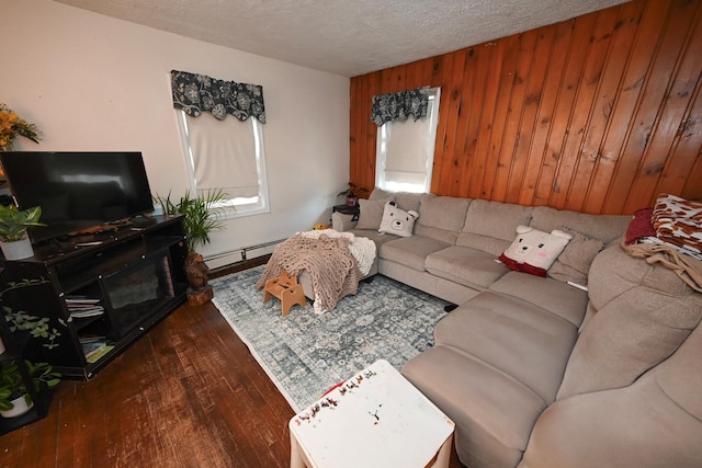 living room featuring dark hardwood / wood-style floors, wooden walls, a textured ceiling, and baseboard heating