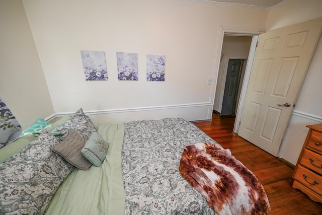 bedroom with ornamental molding and dark hardwood / wood-style floors