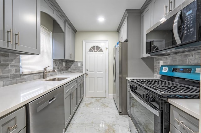 kitchen with stainless steel appliances, sink, gray cabinetry, and backsplash