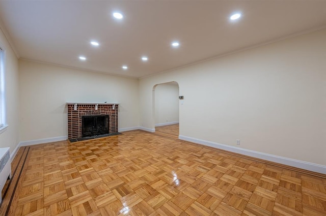 unfurnished living room with a brick fireplace, ornamental molding, and light parquet flooring