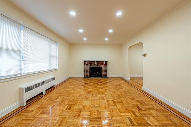 unfurnished living room featuring light parquet flooring, crown molding, radiator heating unit, and a fireplace