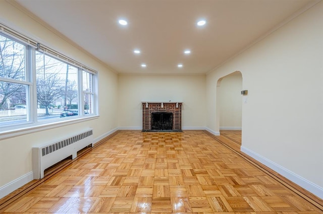 unfurnished living room with ornamental molding, light parquet flooring, a fireplace, and radiator