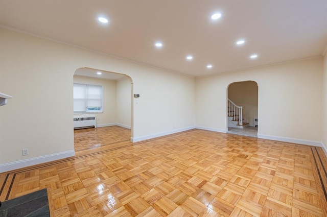 unfurnished room featuring radiator heating unit, ornamental molding, and light parquet floors