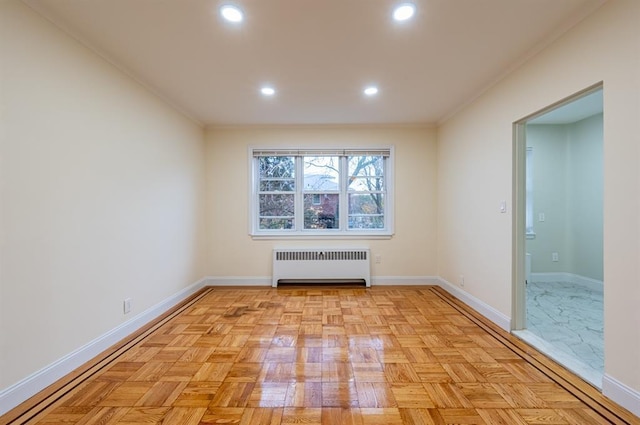 empty room featuring crown molding, radiator heating unit, and light parquet floors