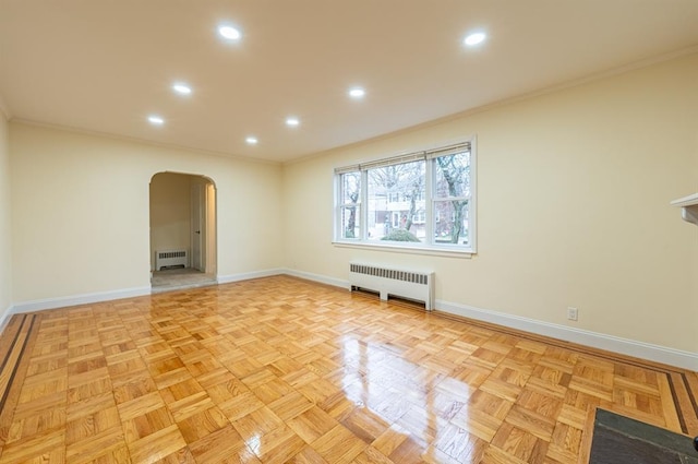 spare room featuring radiator, crown molding, and light parquet flooring