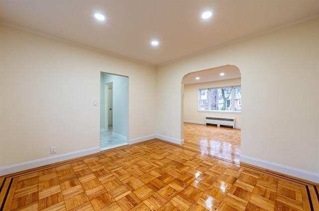 spare room with radiator heating unit and light parquet floors