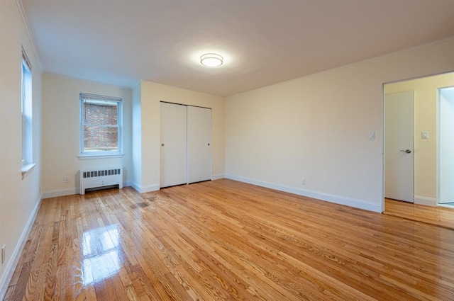 unfurnished bedroom with radiator, a closet, and light wood-type flooring