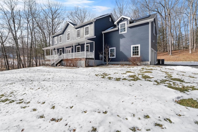 snow covered rear of property with a porch