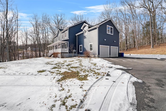 snow covered property with a garage and a sunroom