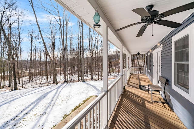 snow covered deck featuring ceiling fan and covered porch