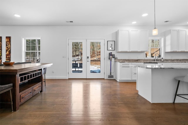 kitchen with a healthy amount of sunlight, hanging light fixtures, and white cabinets