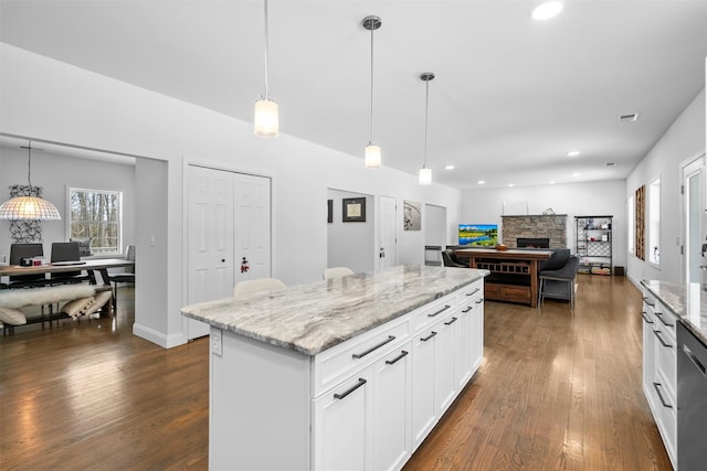 kitchen featuring dark wood-type flooring, decorative light fixtures, a kitchen island, a fireplace, and white cabinets