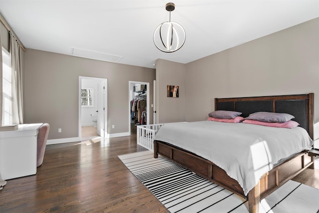 bedroom featuring a closet, dark wood-type flooring, ensuite bath, and a spacious closet