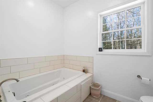 bathroom with tile patterned flooring, tiled tub, and toilet