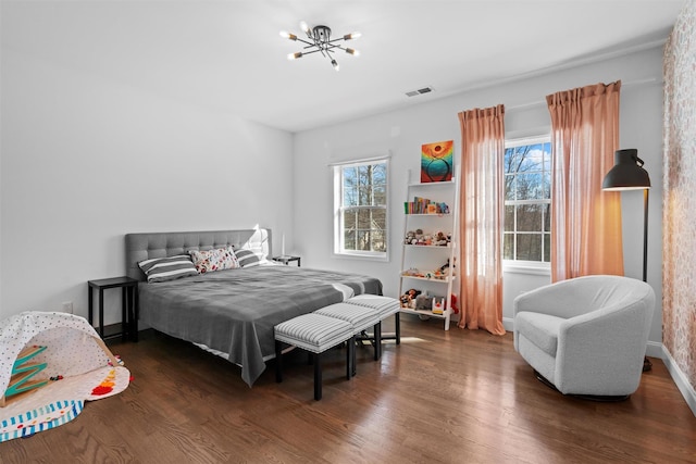 bedroom with dark hardwood / wood-style flooring, multiple windows, and an inviting chandelier