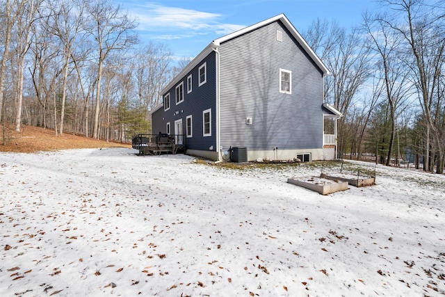 snow covered back of property featuring central AC and a deck