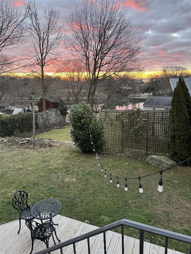 yard at dusk with a deck with water view