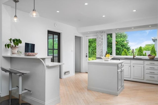 kitchen featuring white cabinetry, a kitchen island, sink, and decorative light fixtures