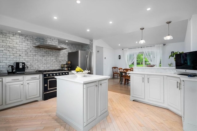 kitchen with stainless steel fridge, double oven range, a center island, white cabinets, and decorative light fixtures