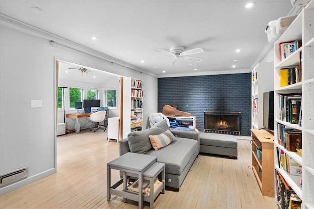 living room featuring a fireplace, light hardwood / wood-style flooring, ornamental molding, and ceiling fan