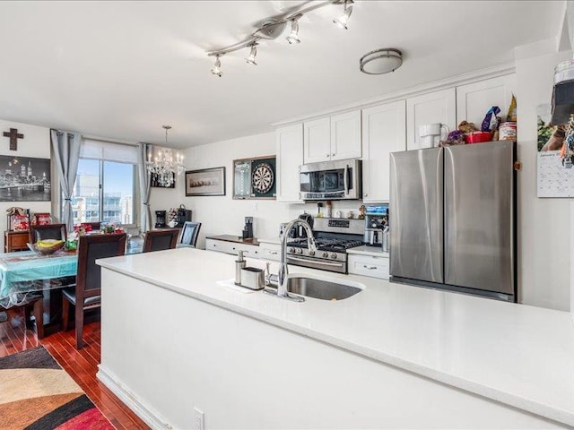 kitchen featuring sink, dark wood-type flooring, hanging light fixtures, stainless steel appliances, and white cabinets