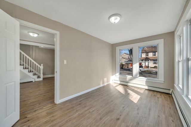 spare room with hardwood / wood-style flooring, a baseboard radiator, and a wealth of natural light