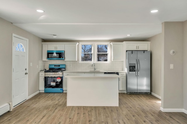 kitchen with sink, tasteful backsplash, a baseboard radiator, stainless steel appliances, and white cabinets