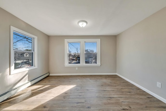 spare room with baseboard heating and light hardwood / wood-style floors