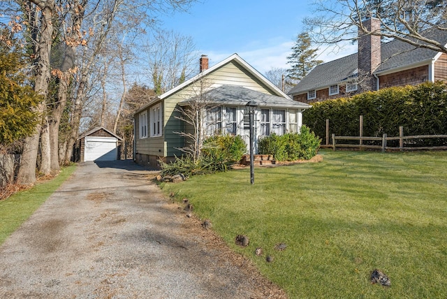 bungalow-style home featuring an outbuilding, a garage, and a front lawn