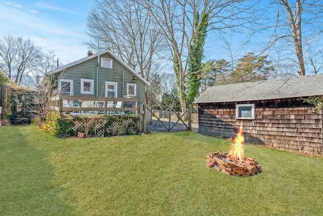 back of house with a fire pit, a lawn, and a deck