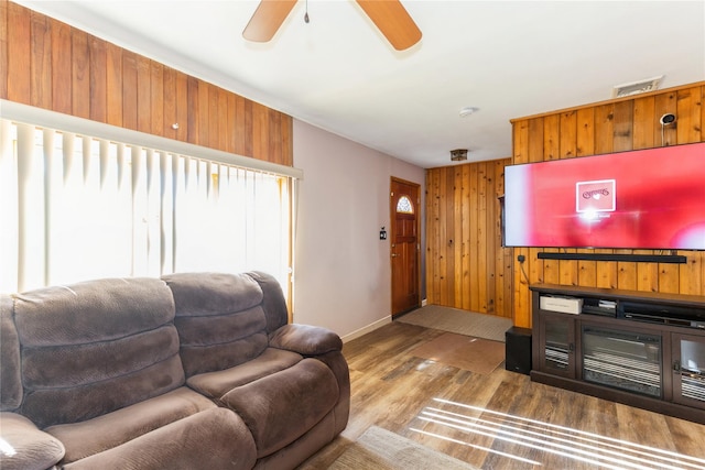 living room featuring ceiling fan, dark hardwood / wood-style flooring, and wood walls