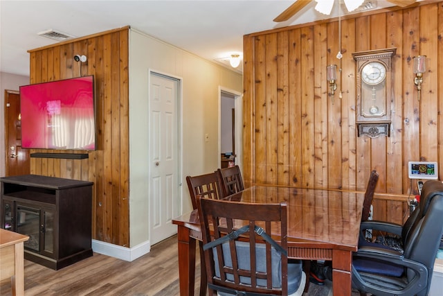 dining space with crown molding, wooden walls, and hardwood / wood-style floors