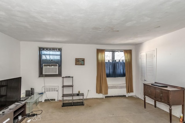 living room with cooling unit, radiator heating unit, carpet floors, and a textured ceiling