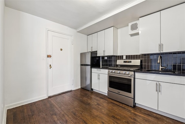 kitchen with tasteful backsplash, dark countertops, stainless steel appliances, white cabinetry, and a sink