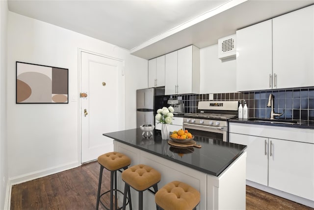 kitchen featuring appliances with stainless steel finishes, dark countertops, a sink, and white cabinets