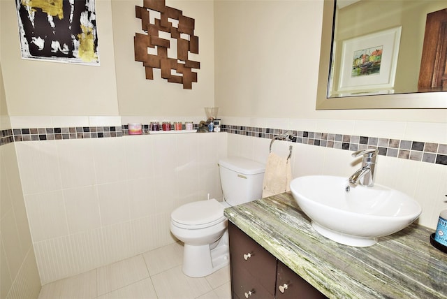 bathroom with tile walls, vanity, tile patterned floors, and toilet