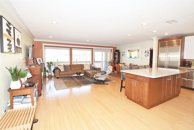 kitchen with a kitchen island, dishwasher, built in refrigerator, light hardwood / wood-style floors, and crown molding