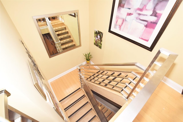 stairway with hardwood / wood-style floors and a high ceiling