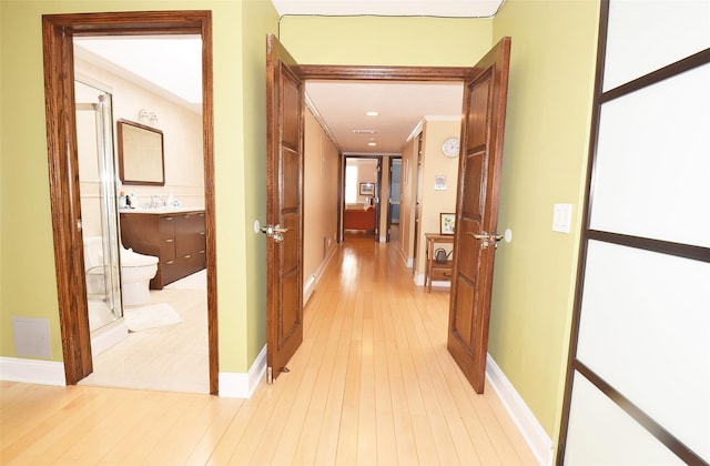 hallway featuring ornamental molding and light hardwood / wood-style floors