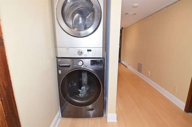 clothes washing area with stacked washer / dryer and light wood-type flooring