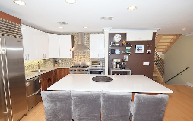 kitchen with sink, tasteful backsplash, a center island, high quality appliances, and wall chimney range hood