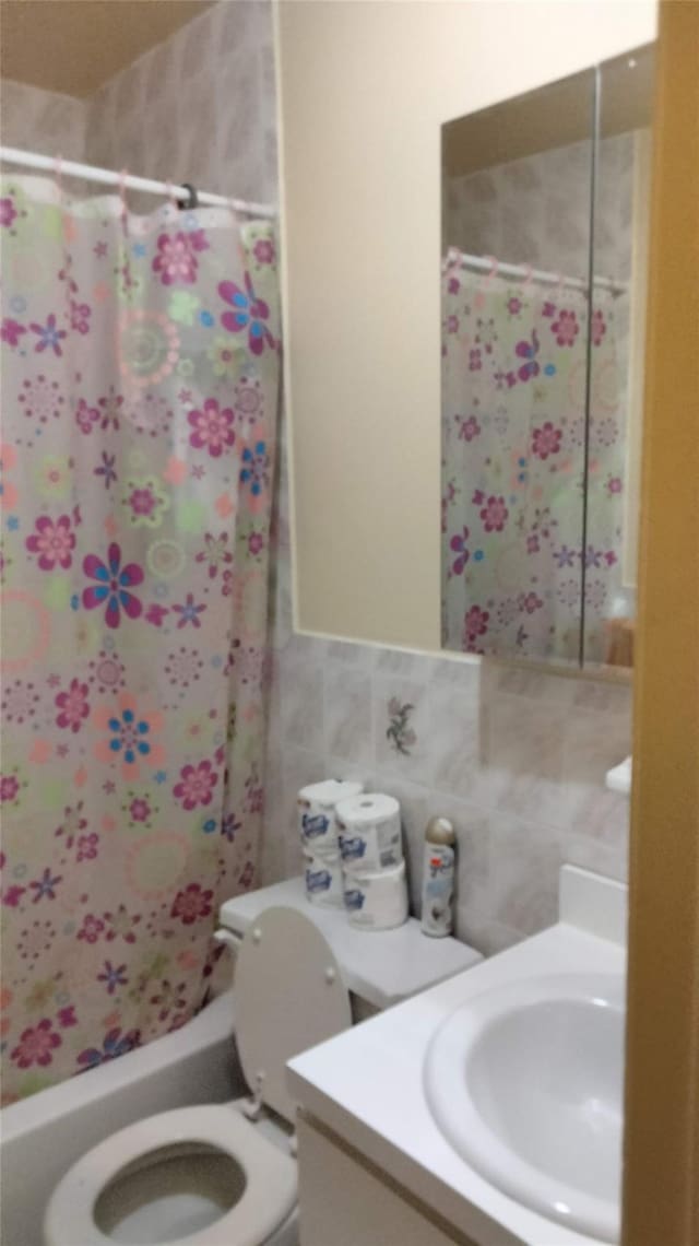 full bathroom featuring tile walls, vanity, toilet, and shower / tub combo with curtain