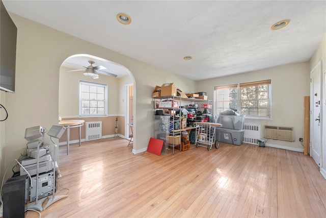 office with radiator heating unit, plenty of natural light, and light wood-style flooring